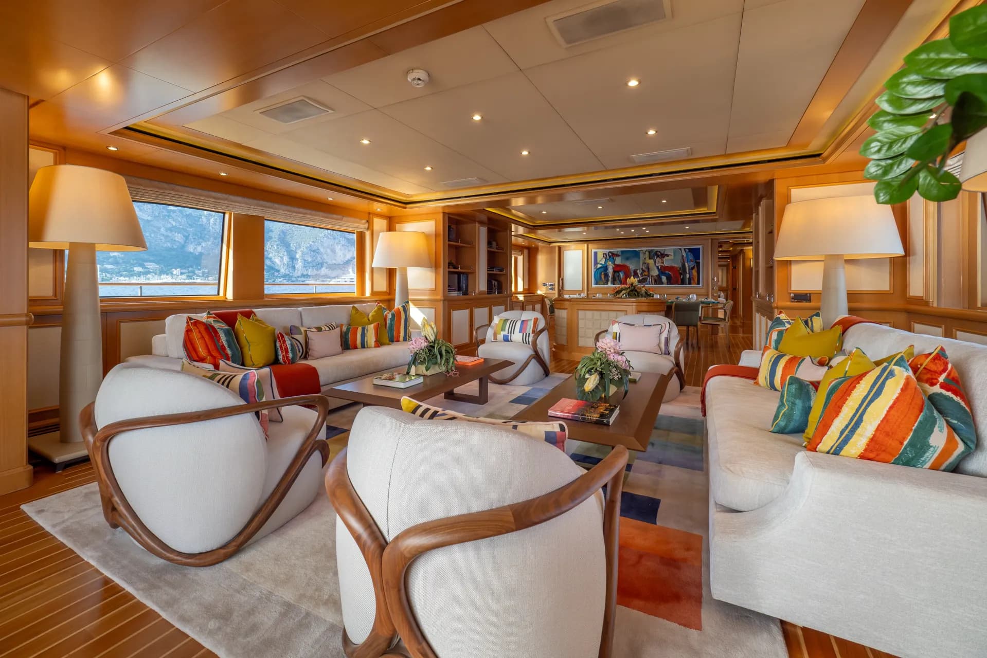 Main saloon in warm wood, soft seating framed by panoramic windows